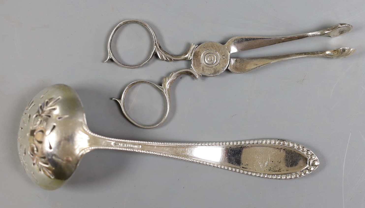 A pair of George III silver sugar nips, George Smith III, London, circa 1780, 11.6cm and a sterling sifter spoon, 2.2oz.